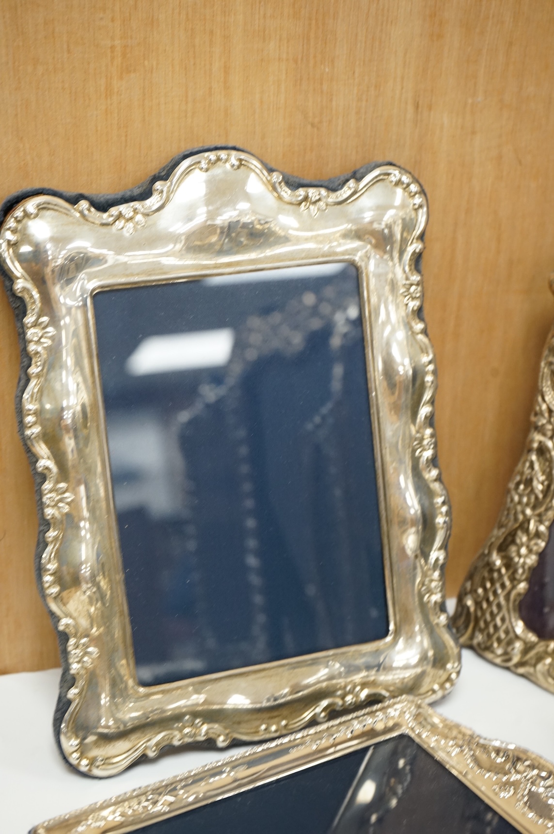 A George V silver mounted rectangular photograph frame, with ribbon bow crest, by Stokes & Ireland Ltd, Chester, 1912, 18.2cm including crest, together with ten other modern silver mounted photograph frames, largest 29.4